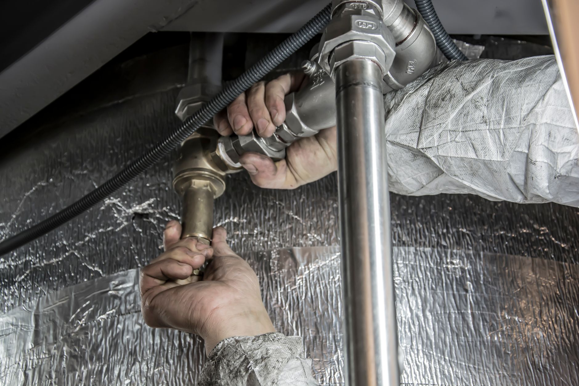 A plumber's hands fitting steel pipes