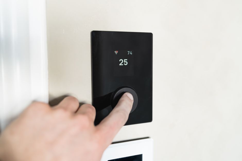 A hand adjusting a smart thermostat
