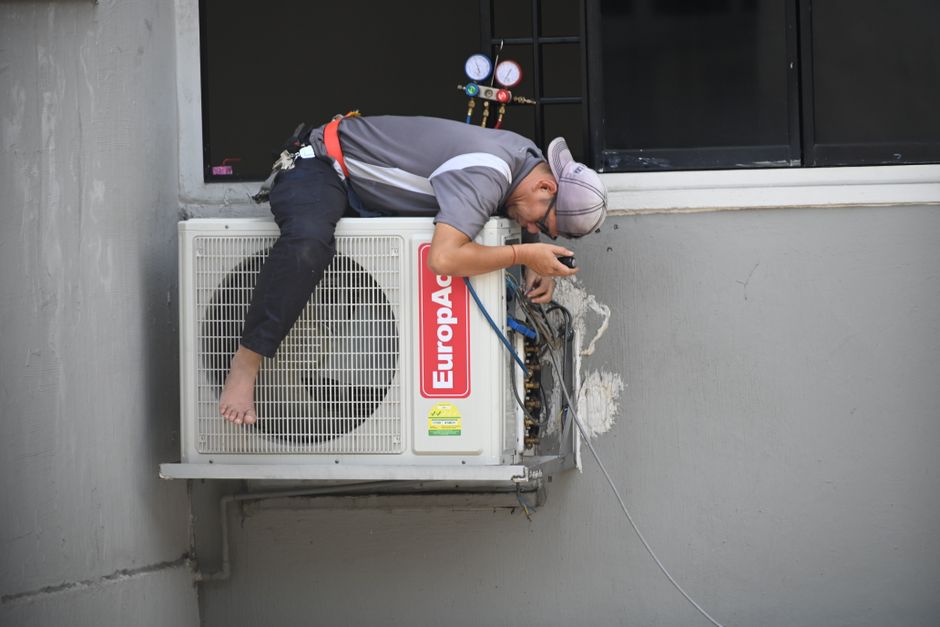 A technician repairing an outdoor AC unit